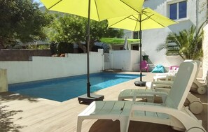 Ein Swimmingpool mit Liegestühlen und einem gelben Sonnenschirm.