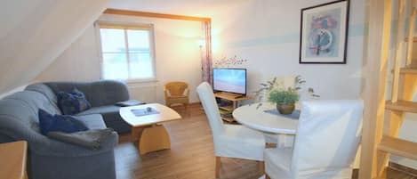 A cozy living room with a sofa, a small table, and a TV.