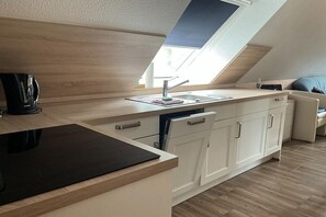 A modern kitchen with a skylight, built-in dishwasher, and a black countertop. - Holiday apartment type 04-S in the attic (Zingst)