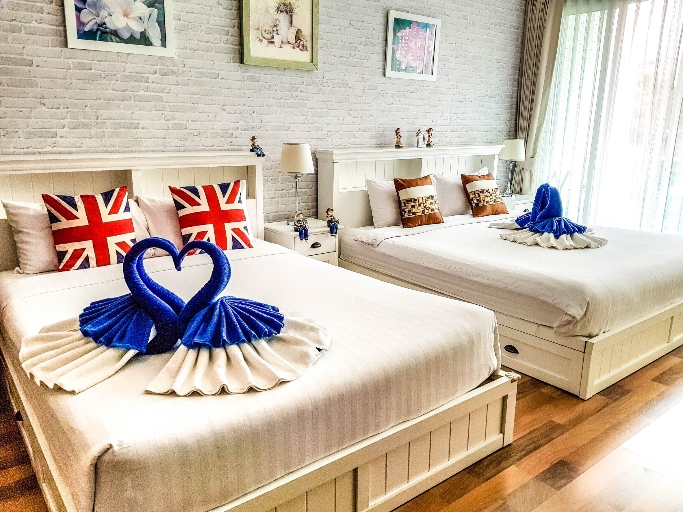 Habitación de hotel con dos camas, una pared de ladrillo y obras de arte en la pared.