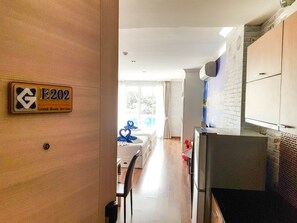A hotel corridor with a sign indicating room service, a dining area with a table and chairs, and a kitchen area with a refrigerator and a pizza box. - E202 Cozy 1-bedroom apartment with Playground near City (Nongkae)