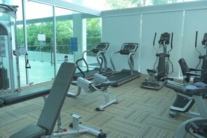 Ein Fitnessstudio mit Laufbändern, Crosstrainern und Gewichten.