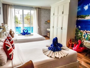Een hotelkamer met twee bedden, een groot raam met gordijnen, een kledingkast en uitzicht op een zwembad en gebouwen.