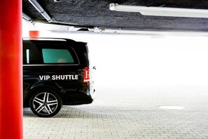Um SUV preto com a inscrição 'VIP SHUTTLE' na lateral estacionado em área coberta.