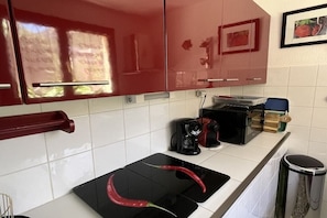Eine Küche mit roten Schränken, einer schwarzen Arbeitsplatte, einer Kaffeemaschine und einem Mülleimer.