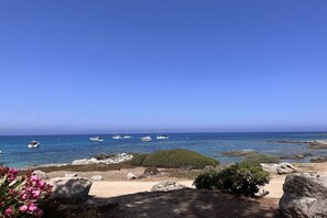 A coastal landscape with rocky terrain, a sandy beach, and a clear blue sky. - Holiday home in Lumio with swimming pool (Lumio)
