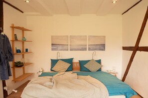 A bedroom with a bed, a nightstand, a shelf with items, and a painting on the wall. - Holiday apartment with 5 bedrooms (Strachau)