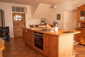 Une cuisine avec des meubles de rangement en bois, un four encastré, un évier et une cuisinière.