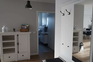A modern interior with a white cabinet, a hanging light fixture, and a doorway leading to a kitchen area. - Holiday apartment in Boizenburg with sauna (Boizenburg)