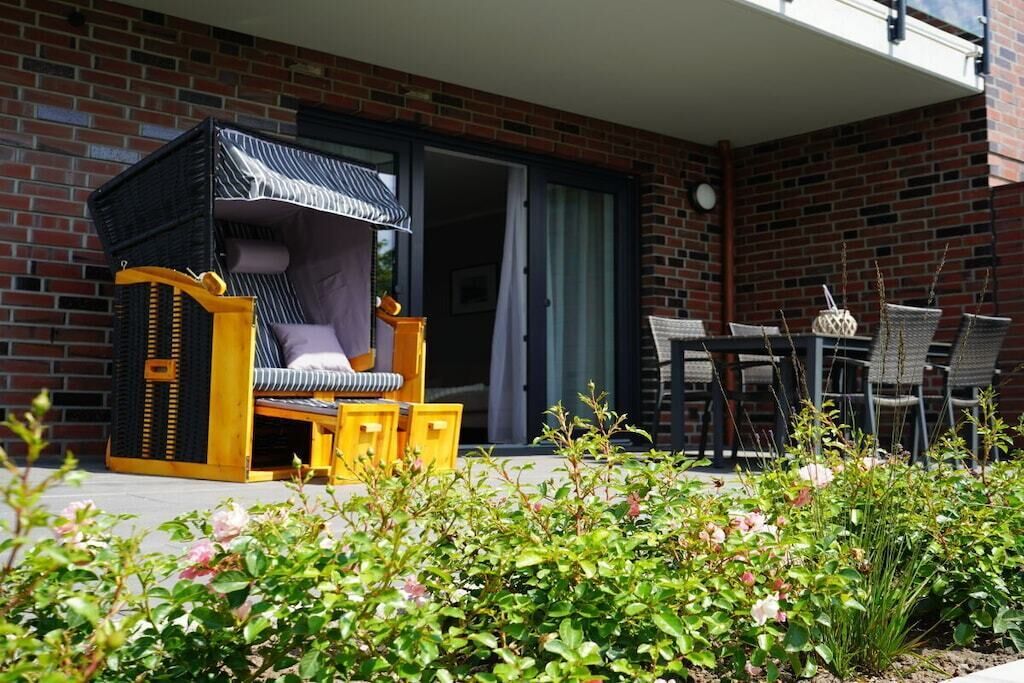 A patio area with a wooden bench, a table, and chairs.