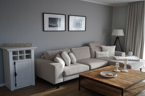 A neutral-toned living room with a sofa, a coffee table, a side table, and a lamp. - Holiday apartment in Boizenburg with sauna (Boizenburg)