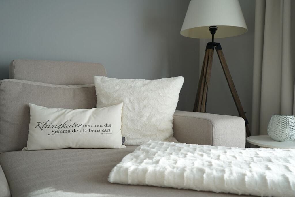Ein Schlafzimmer mit einem Bett, Kissen, einer Nachttischlampe und einem kleinen Tisch.