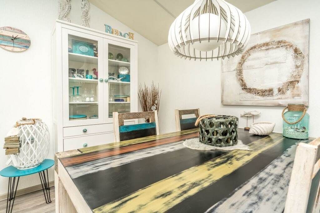 A dining area with a black and yellow table, white cabinets, and a pendant light.