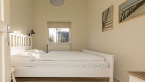 A bedroom with a single bed, a window, and a radiator. - Holiday home with 2 bedrooms (Burgh-Haamstede)