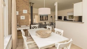 A modern interior with a dining area featuring a white table and chairs, a woven basket centerpiece, and a hanging light fixture. - Holiday home with 2 bedrooms (Burgh-Haamstede)