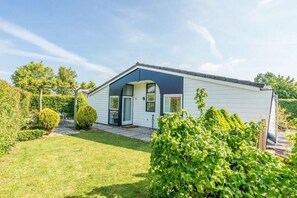 A single-story house with a front porch, a small garden, and a clear sky. - Holiday home in Renesse with swimming pool (Renesse)