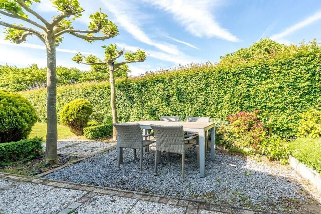 An outdoor seating area with a table and chairs, surrounded by gravel and greenery.