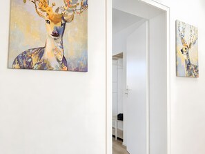Ein Flur mit zwei Bildern an den Wänden, eines zeigt einen Hirsch, das andere ein Kaninchen.