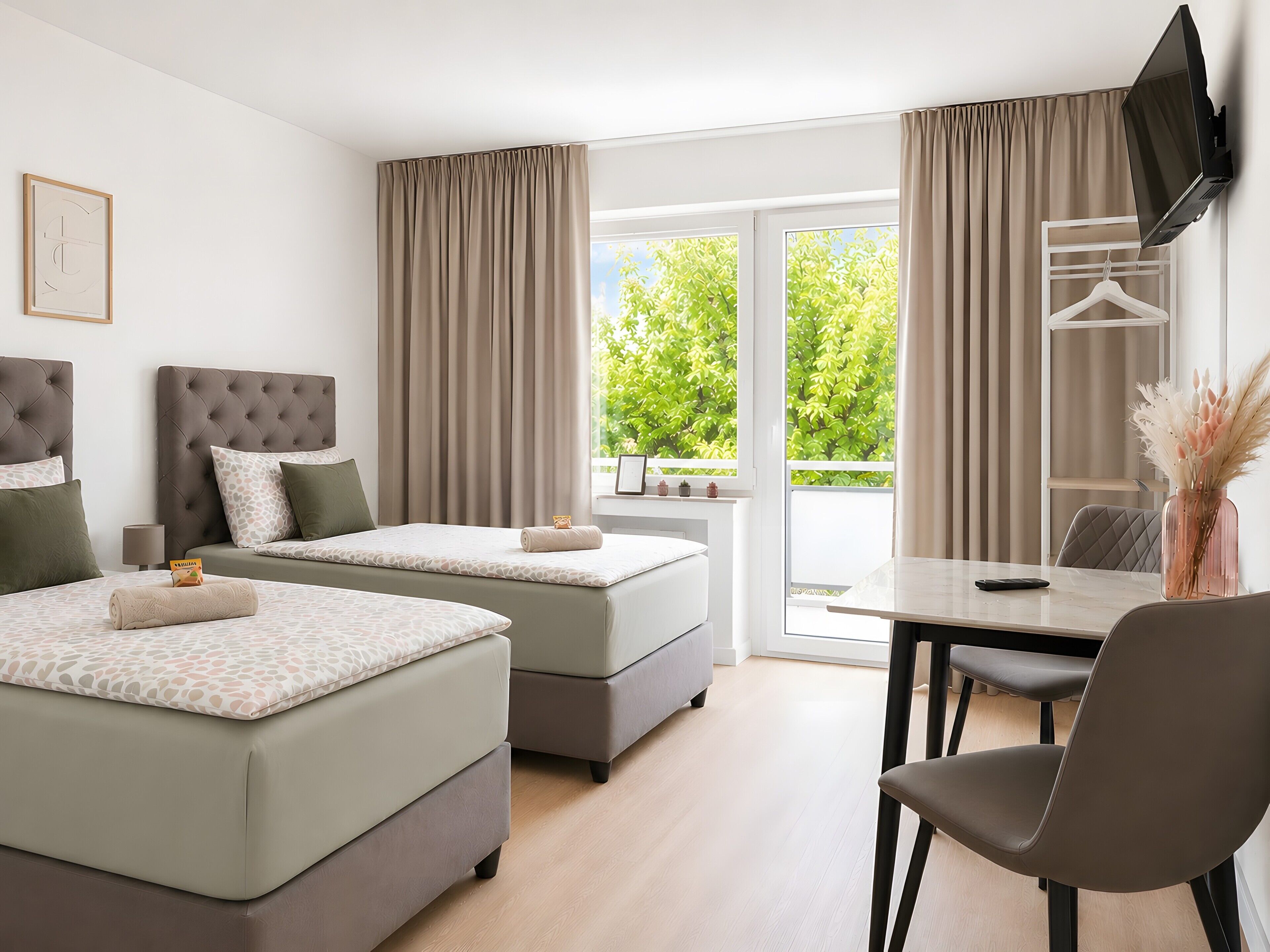 A hotel room with two beds, a desk, and a TV.