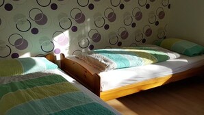 Quarto com duas camas de solteiro, cabeceiras de madeira e papel de parede estampado.