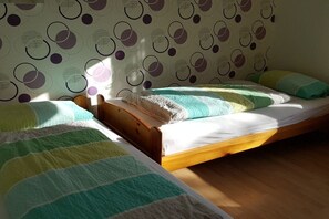 A room with two single beds, wooden headboards, and a patterned wallpaper. - Holiday apartment with 2 bedrooms (Norden-Norddeich)
