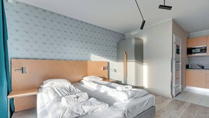 Ein modernes Hotelzimmer mit einem großen Bett, einem Nachttisch, einem Einbauschrank und einer Küchenzeile.