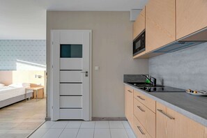 Une cuisine de taille réduite, équipée d’un four à micro-ondes, d’une cuisinière et de meubles de rangement en bois.
