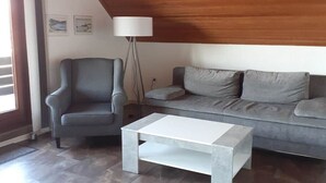 Ein Wohnzimmer mit grauem Sessel, grauem Sofa und weißem Couchtisch.