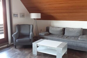 Ein Wohnzimmer mit grauem Sessel, grauem Sofa und weißem Couchtisch.