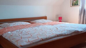 Ein Standard-Einzelbett mit Holzrahmen, eine rote Nachttischlampe und ein an der Wand hängendes Bild.
