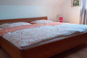 Ein Standard-Einzelbett mit Holzrahmen, eine rote Nachttischlampe und ein an der Wand hängendes Bild.