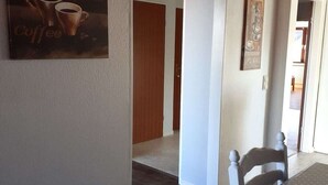 Ein Flur mit Wandkunst zum Thema Kaffee, einer Holztür und einem weißen Stuhl.