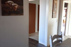 Ein Flur mit Wandkunst zum Thema Kaffee, einer Holztür und einem weißen Stuhl.