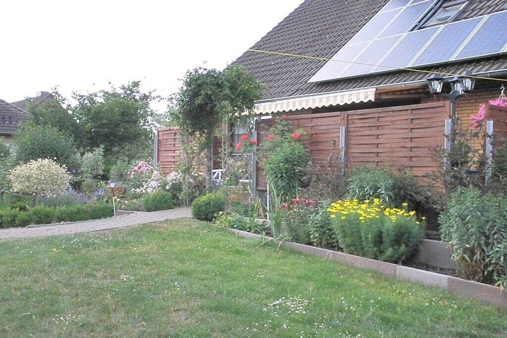 A residential property with a garden, a solar panel on the roof, and a brick house.
