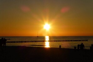 Ein Sonnenuntergang über dem Meer mit einem Steg, der sich ins Wasser erstreckt.