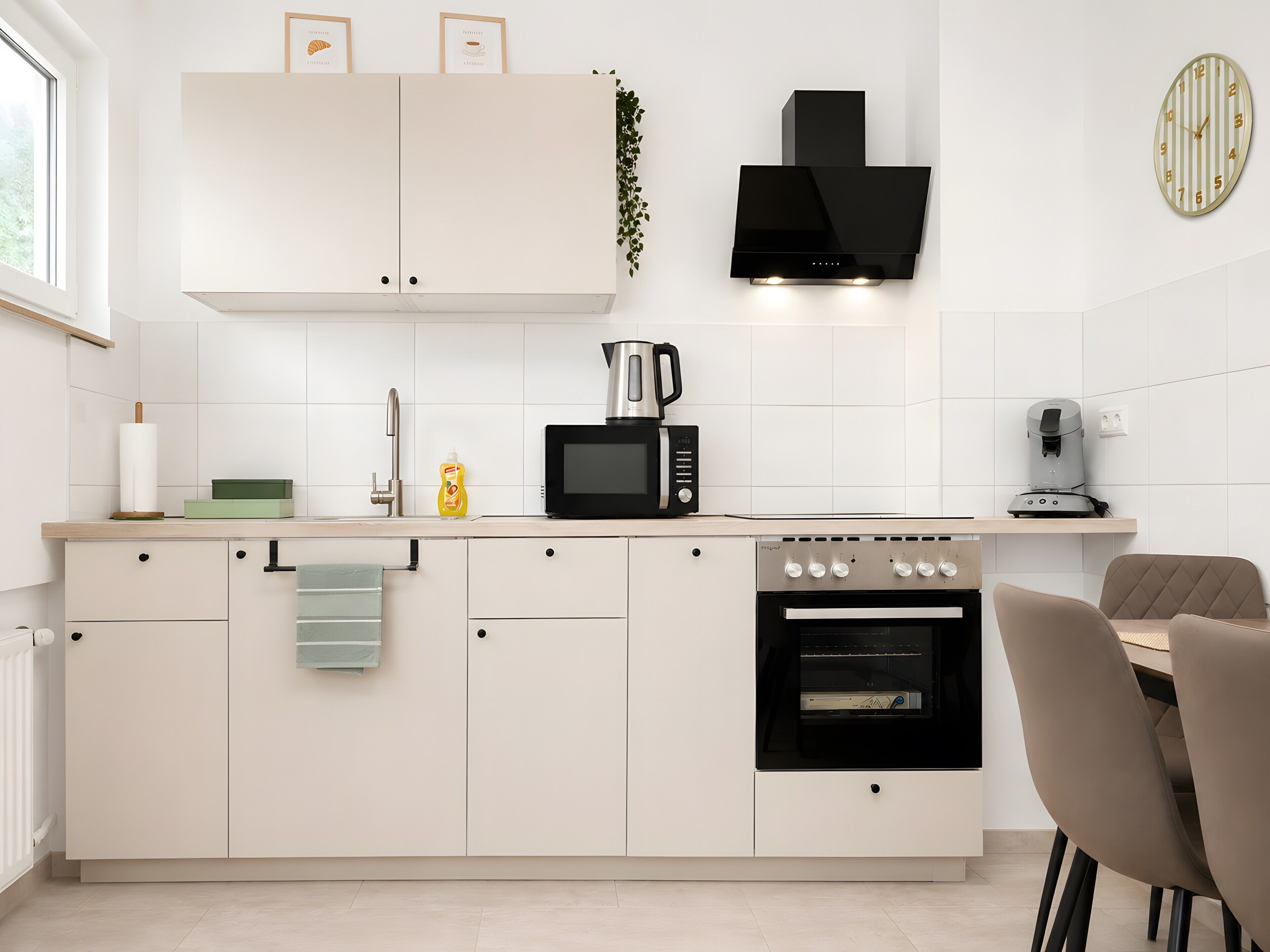 A modern kitchen with white cabinets, a black range hood, a microwave, a coffee machine, and an oven.