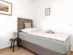 A bedroom with a bed, a bedside table, a lamp, a framed picture on the wall, and a motivational quote poster. - Loft44 – Centrally Located, Balcony, Renovated, Parking, Balcony and Wi-Fi for 5 Guests (Oberhausen)