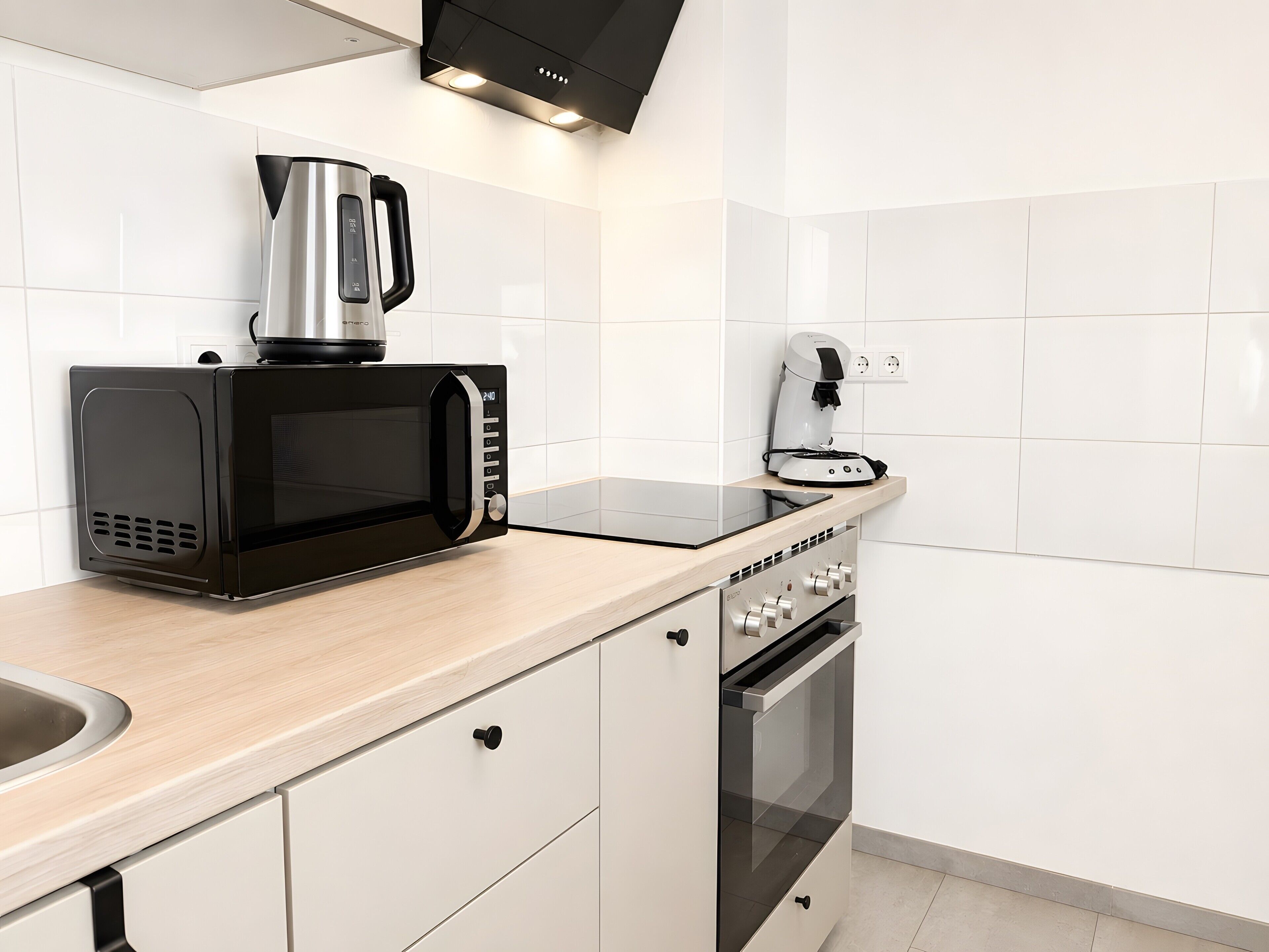 A modern kitchen with a microwave, coffee maker, and oven.