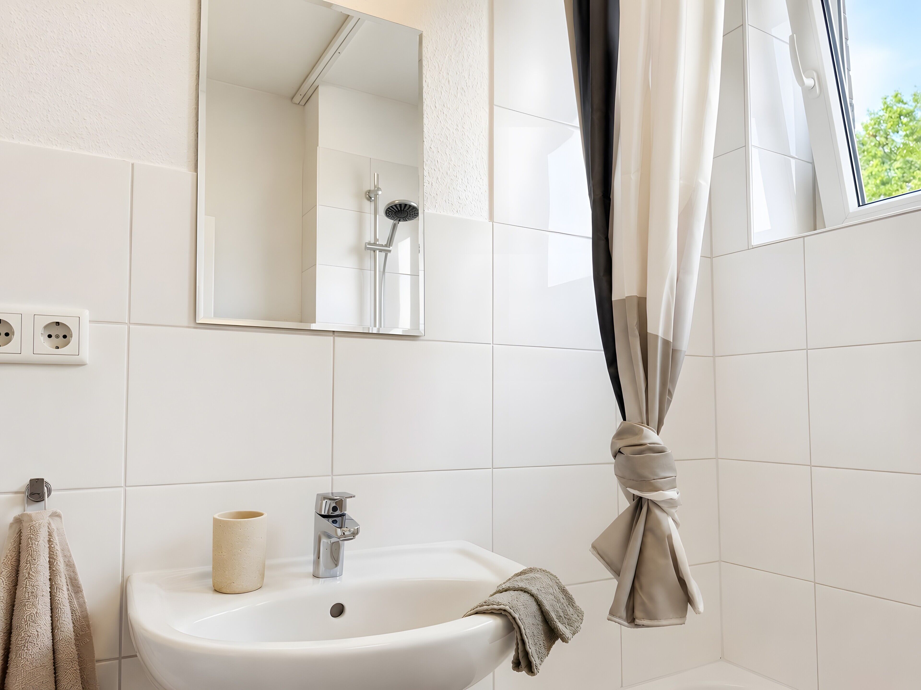 A bathroom with a sink, mirror, and shower.