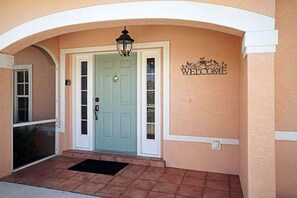 A house entrance with a light blue door, a welcome sign, and a black lantern above the door. - CCVS - Villa Blue Lagoon (Cape Coral)