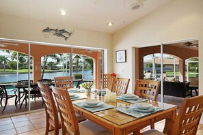 Un coin repas avec vue sur un plan d’eau, des chaises en bois et une table dressée pour quatre personnes.