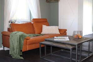 Una sala de estar con un sofá, una mesa de centro y un ventanal con cortinas.