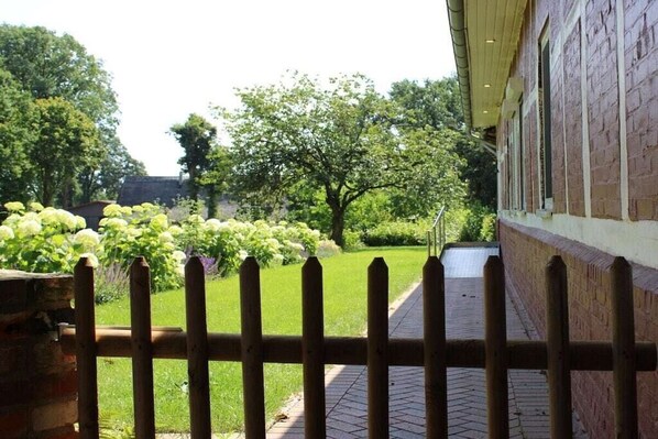 A brick building with a paved pathway leading to a wooden gate. - Holiday apartment with 1 bedroom (Heeslingen)