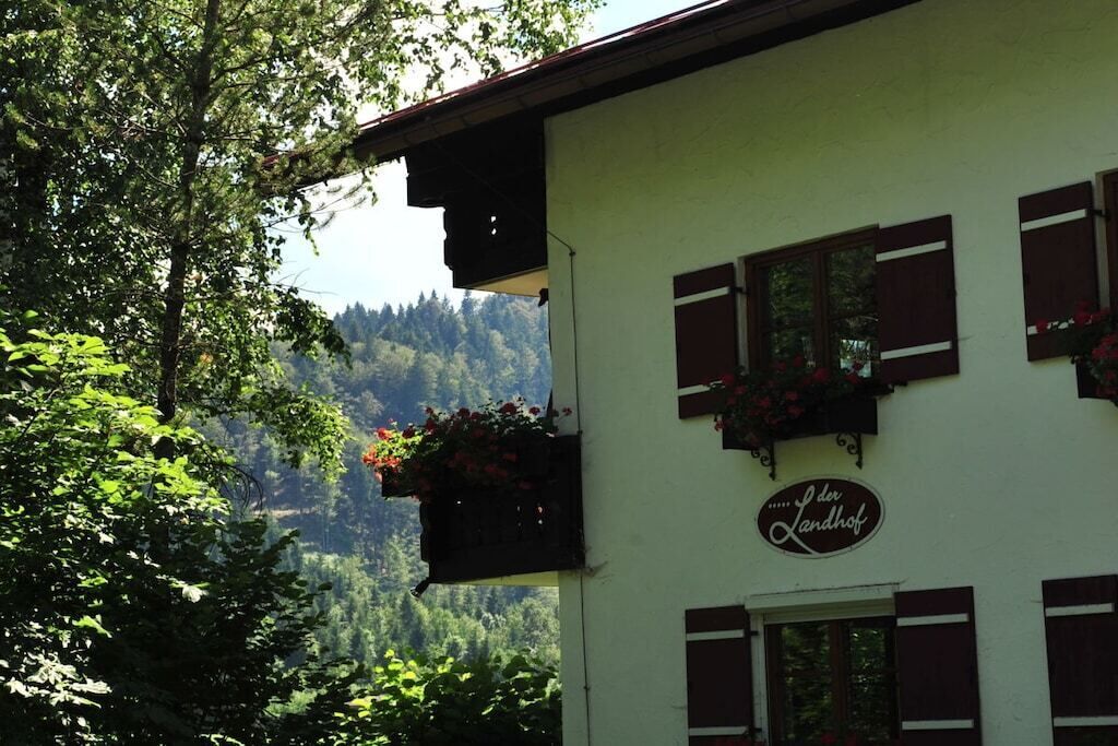 A building with a sign reading 'der Landhof' and flower boxes on the windowsills.