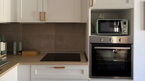 A modern kitchen with white cabinetry, a microwave, and an oven.