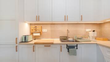 Eine moderne Küche mit weißen Schränken, einer Edelstahl-Spüle und einer Holzausziehtafel.