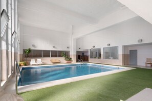 Een binnenzwembad met uitzicht op de omgeving, inclusief een sauna en zitplaatsen.