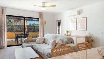 Ein modernes Wohnzimmer mit einer Couch, Sesseln, einem Tisch und einem Deckenventilator.