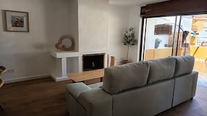 A living room with a fireplace, a sofa, a dining table, and a ceiling fan.