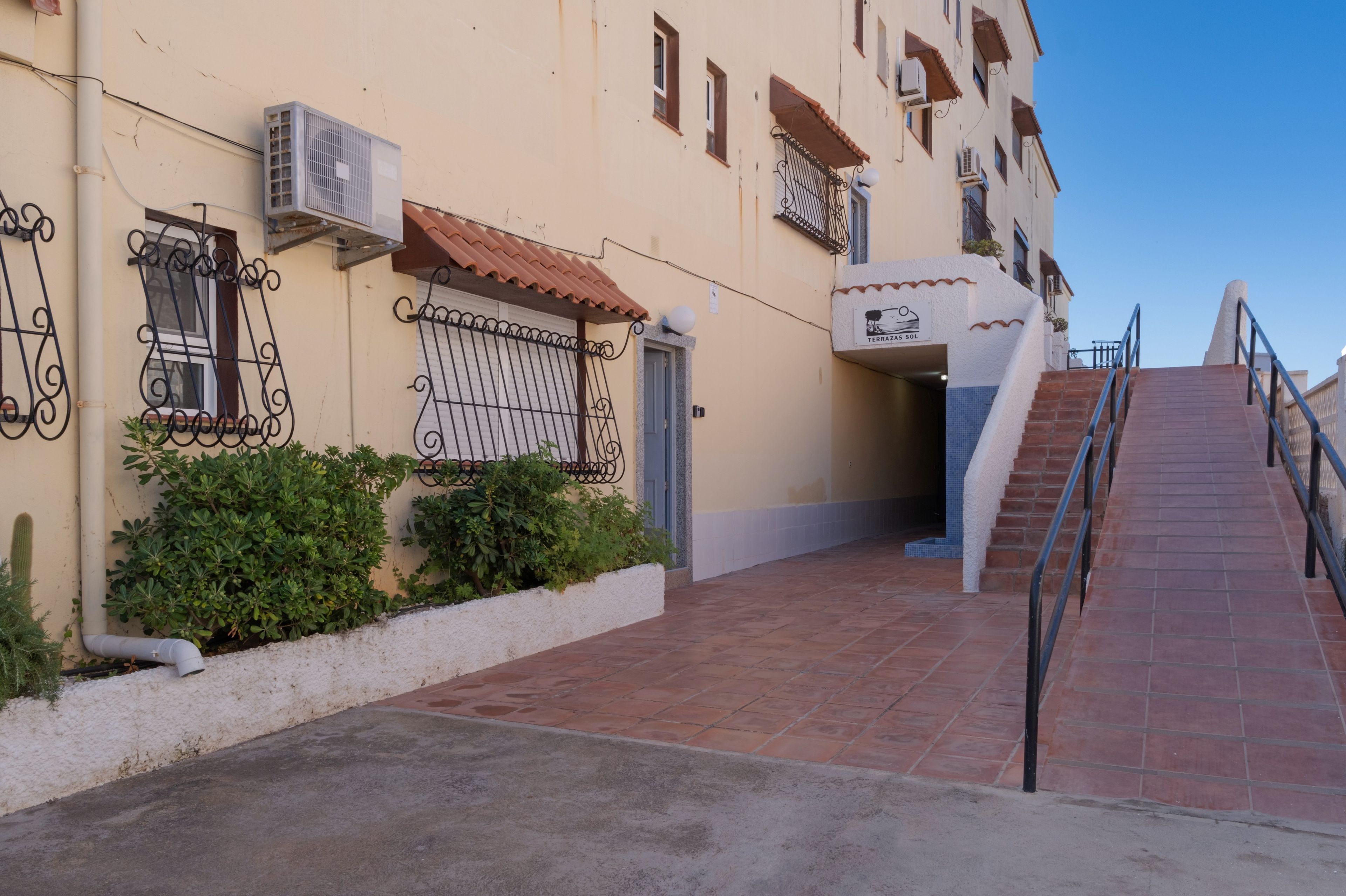 A building with a tiled entrance, a staircase, and a sign indicating a terrace.